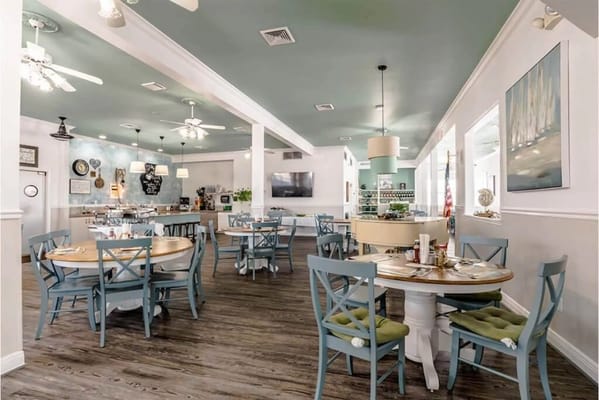 Brightly lit dining area with wooden tables and blue chairs