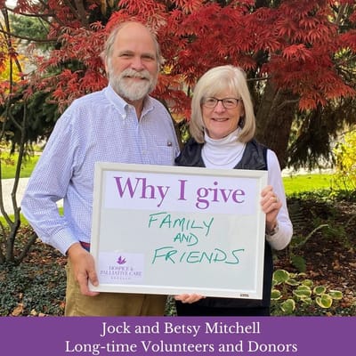Two volunteers holding a sign in a garden