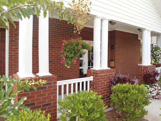A view of the entrance area featuring white columns and hanging flower baskets.