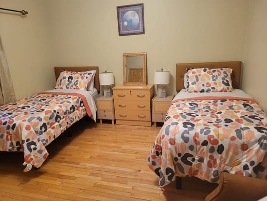 A cozy resident room with two beds and a dresser