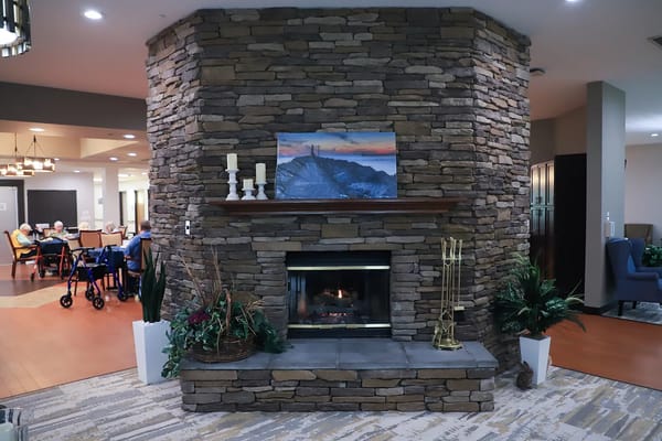 Stone fireplace in a cozy common area with chairs and tables