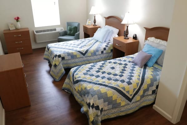 A cozy resident room with twin beds and natural lighting