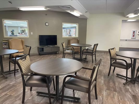 A cozy lounge area with tables and chairs at Pine Acres Rehabilitation & Care Center.