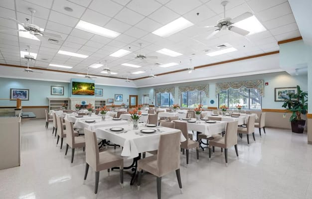 Spacious dining room with neatly arranged tables and floral centerpieces.