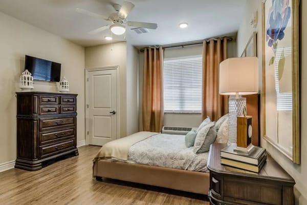 Cozy resident room with a bed, dresser, and lamp