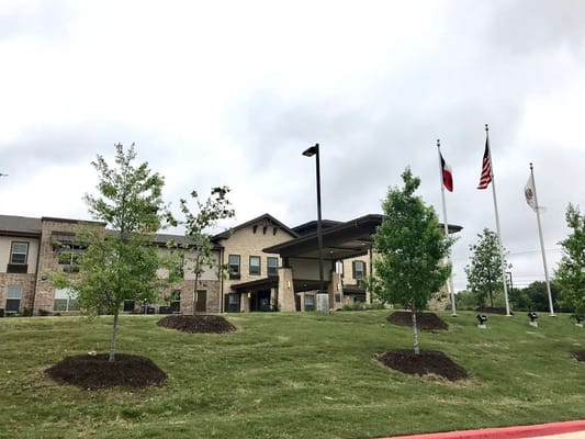 Front entrance of Isle at Watercrest - Dominion with landscaped area and flags.
