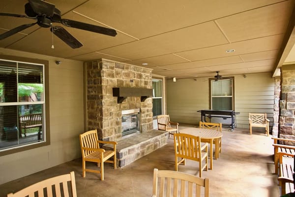 Outdoor seating area with a stone fireplace at Isle at Watercrest Mansfield.