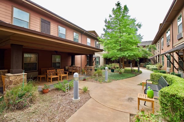 Pathway in the courtyard with seating and greenery at Isle at Watercrest Mansfield.