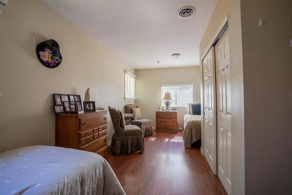 Spacious bedroom with two beds and wooden furniture in a senior living facility