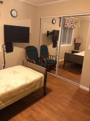 Comfortable resident room featuring a bed, two chairs, and a TV.