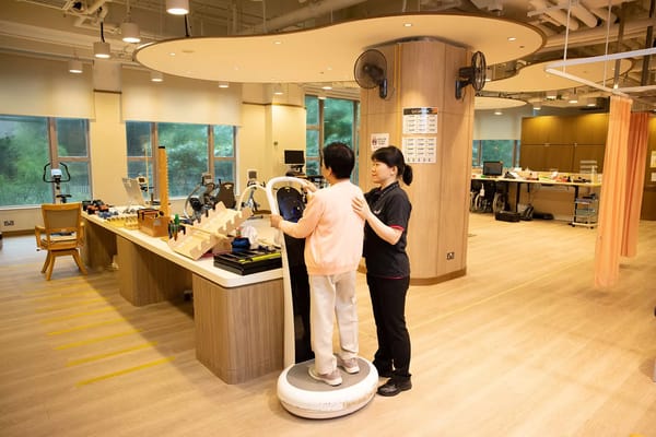 Staff assisting a resident in a therapy room