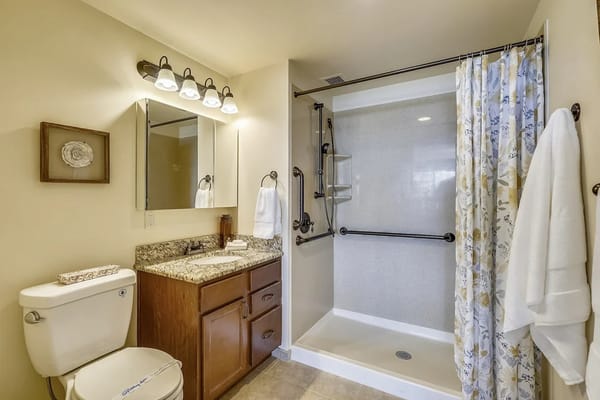 Spacious bathroom featuring a shower, toilet, and granite countertop.