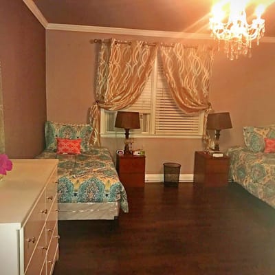 A well-decorated bedroom with two beds, nightstands, and a chandelier.