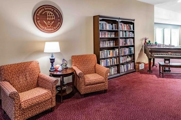 Lounge area with two chairs, a lamp, and a bookshelf