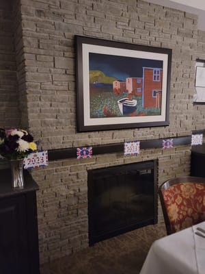 Decorative dining area featuring a stone fireplace and colorful wall art.