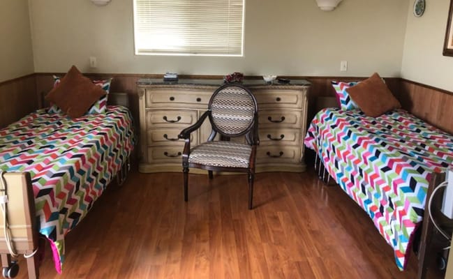 A colorful bedroom with two beds and a chair.