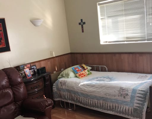 A cozy bedroom featuring a metal bed, colorful pillow, and wooden furniture.