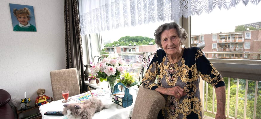 An elderly resident in a cozy living room with personal items