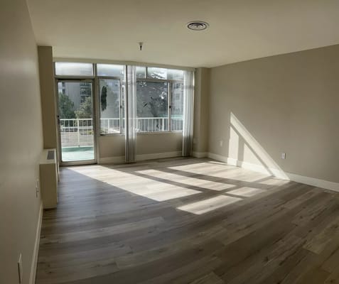 Well-lit interior room with large windows and wood flooring
