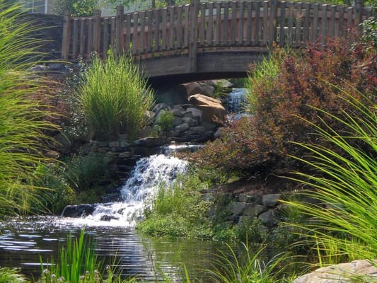 A scenic view of a bridge over a small waterfall