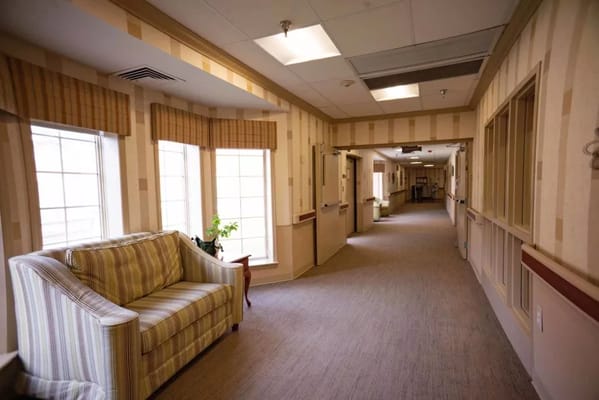 A well-lit corridor with seating area in a nursing home