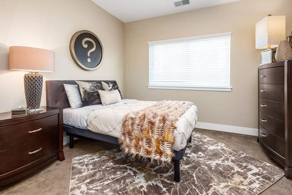 Modern bedroom with a bed, decorative pillows, and stylish lamp