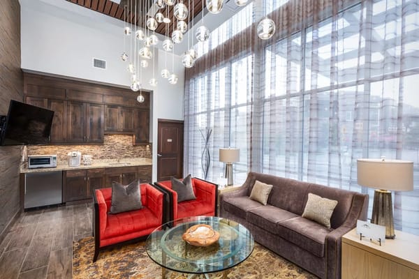 Cozy lounge with red and gray seating, modern lighting, and large windows