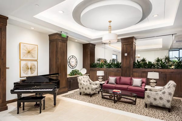 A grand lobby featuring a piano, plush seating, and decorative plants.