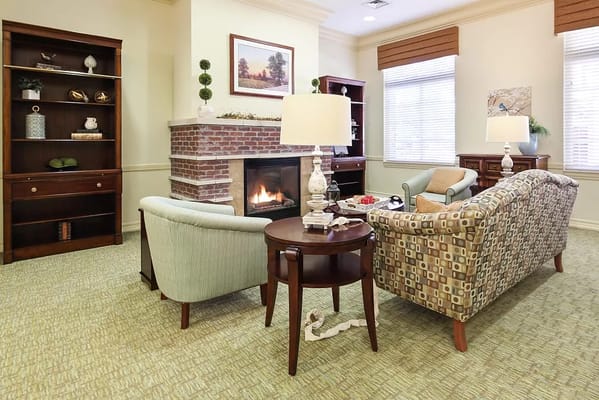 A cozy living room with a fireplace, seating area, and bookshelf.