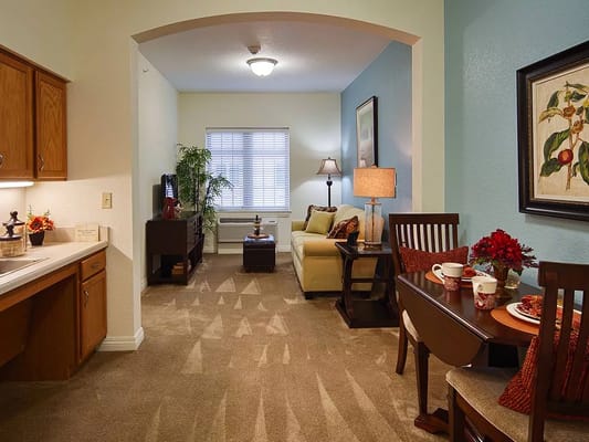 Comfortable living area with a couch and dining table in an assisted living facility.
