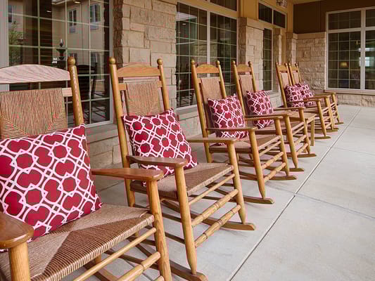 Row of wooden rocking chairs with decorative red pillows