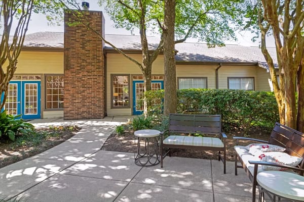 Seating area with benches and small tables surrounded by greenery