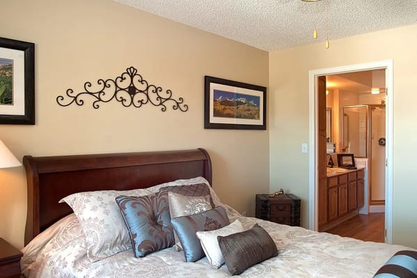 Interior view of a cozy bedroom with a wooden bed and decorative wall art.