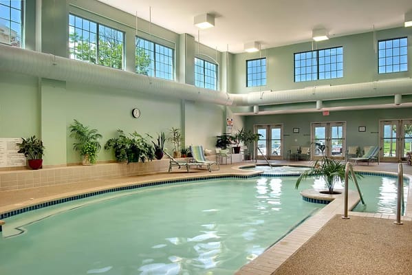 Indoor swimming pool with large windows and lounge chairs