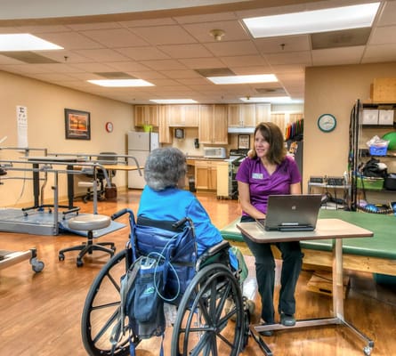 Staff member assisting a resident in a rehabilitation room