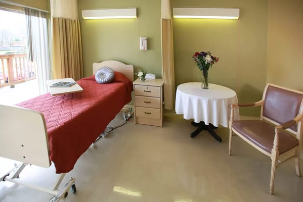 An inviting resident room with a bed, table, and flowers.