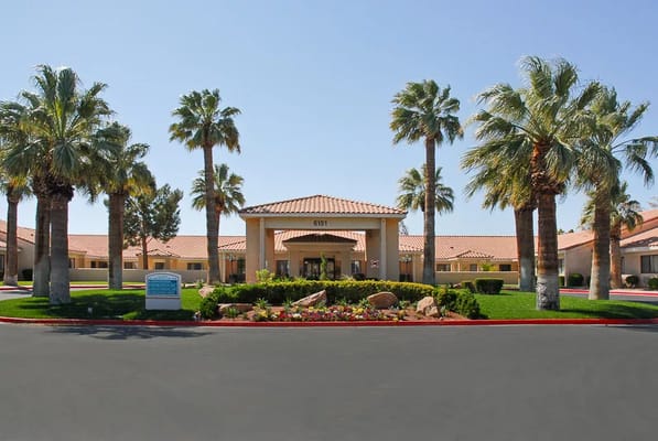Front entrance of Life Care Center of Las Vegas with palm trees and flower beds