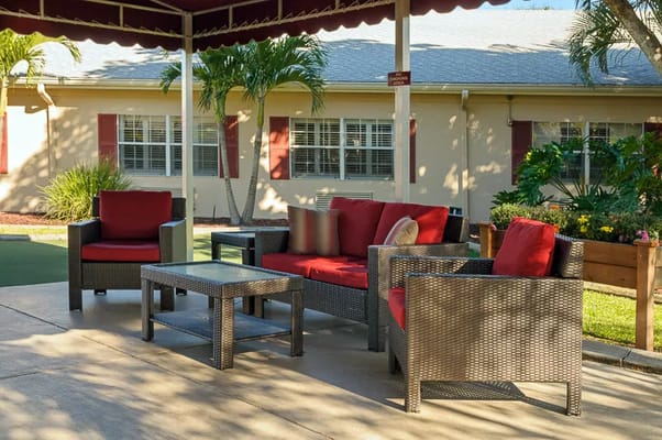 Outdoor seating area with red cushions and greenery