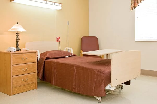 A well-furnished bedroom with a bed, lamp, and side table