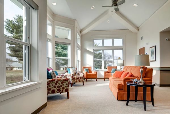 Bright and inviting living room with orange couch and floral chairs
