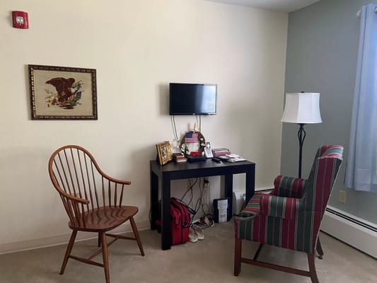 Living room setup with wooden chair, striped armchair, and TV.