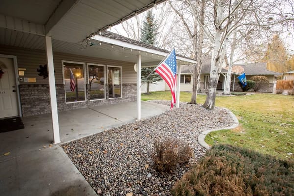 Entrance of a senior living facility with garden and flags