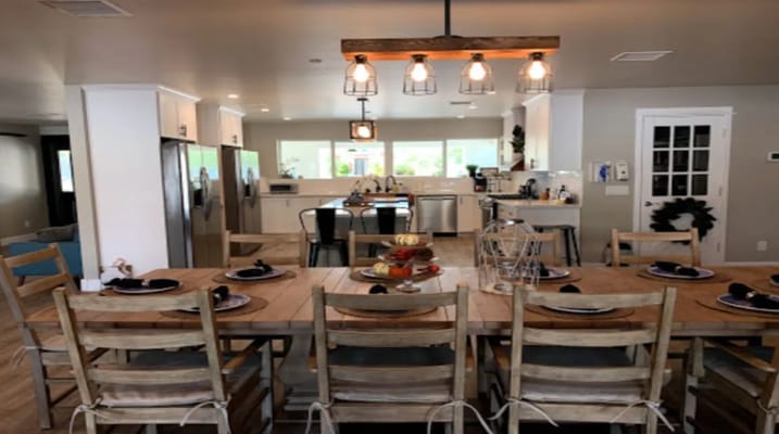Modern dining area with a large wooden table and kitchen