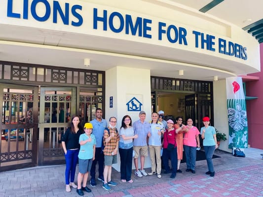 Staff and residents posing in front of the facility entrance