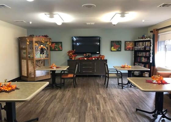 Common area decorated for fall with tables and a TV