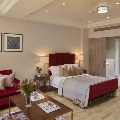 A well-furnished resident room with a bed and seating area