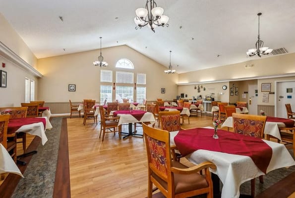 A dining room with wooden chairs and red tablecloths at Lucas Court.