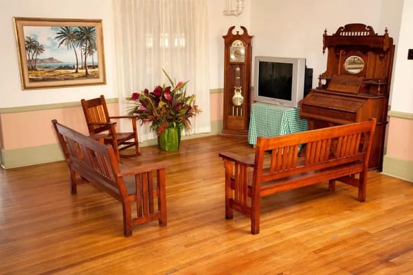 A warm living room with wooden benches, a clock, and a piano.