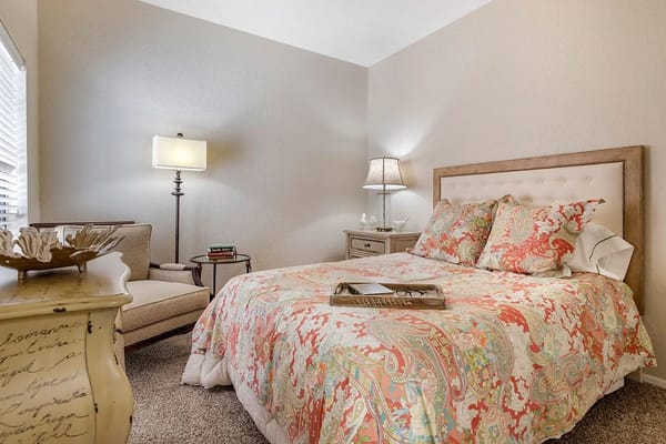 Comfortable bedroom with a floral quilt and seating area