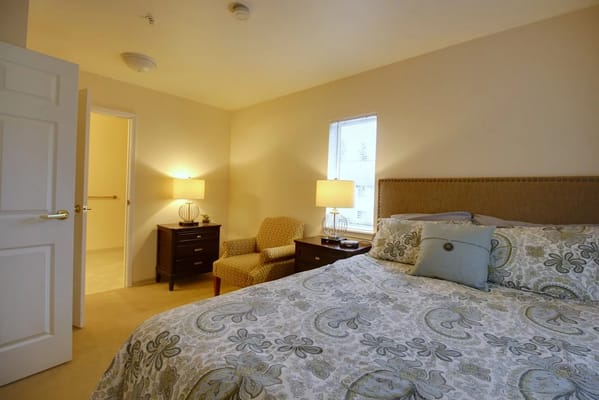 A well-furnished bedroom with a bed, armchair, and bedside tables.
